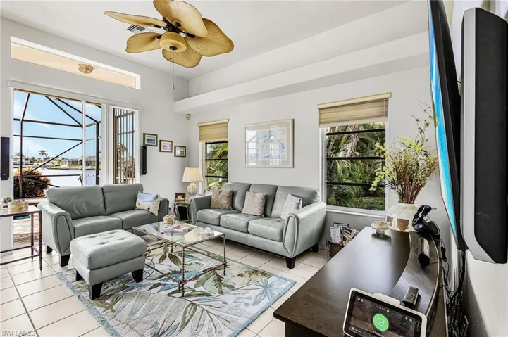 Living area featuring ceiling fan, light tile patterned floors, a water view