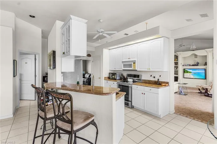 Kitchen with ceiling fan, white cabinets, a breakfast  bar, and stainless steel range with electric stovetop
