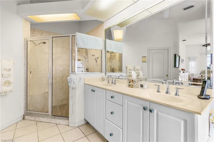 Primary Bathroom with a shower stall, double vanity, and light tile patterned floors