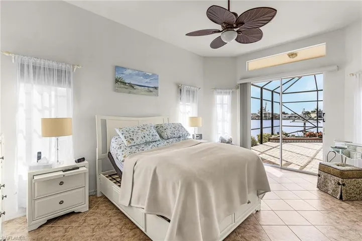Bedroom with access to exterior, a sunroom, a water view, a ceiling fan, and light tile patterned floors