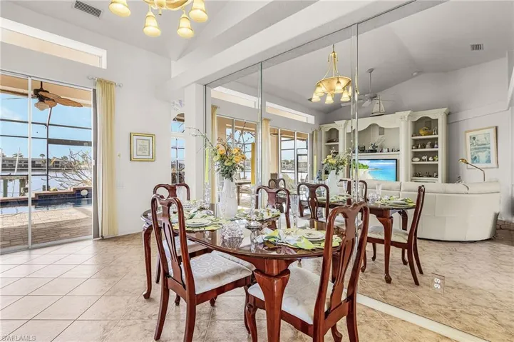 Dining area featuring a ceiling fan, vaulted ceiling, hanging lights, and light tile porcelain patterned floors