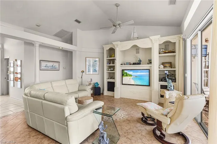 Living room featuring ceiling fan, vaulted ceiling, and light tile patterned floors
