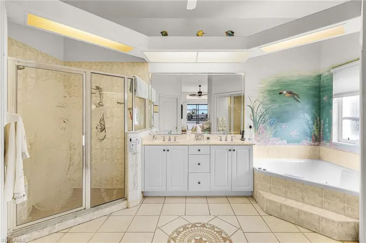 Primary Bathroom featuring a ceiling fan, double vanity, a walk in shower, and a garden tub
