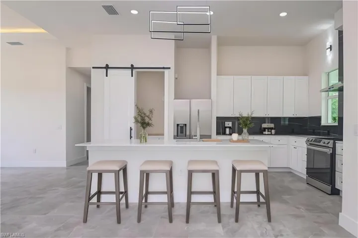 Kitchen featuring a kitchen breakfast bar, an island with sink, stainless steel appliances, and white cabinetry