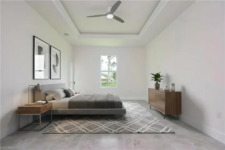 Bedroom featuring ceiling fan, a tray ceiling, and concrete flooring
