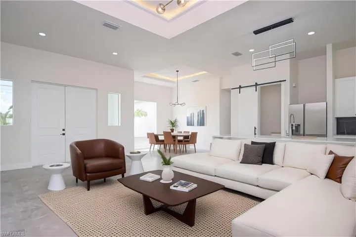 Living area with a barn door, recessed lighting, and a high tray ceiling