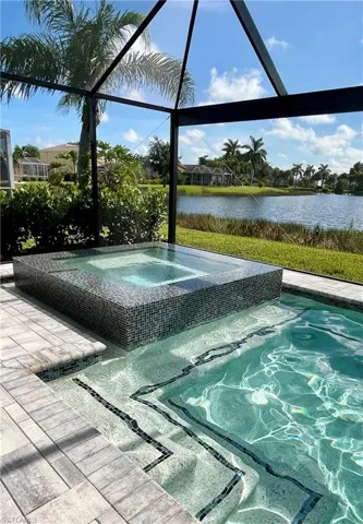 View of pool featuring a lanai, an in ground hot tub, and a water view