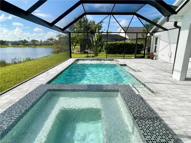 View of swimming pool featuring a water view, a yard, a patio, and glass enclosure