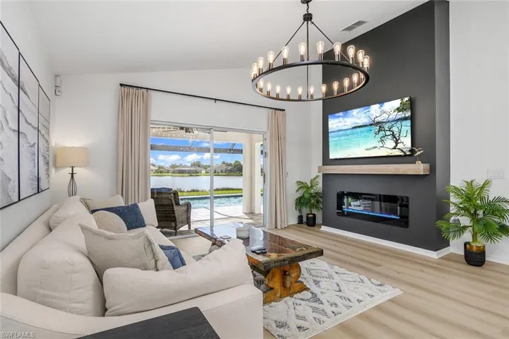 Living room with vaulted ceiling, light wood-type flooring, and a chandelier