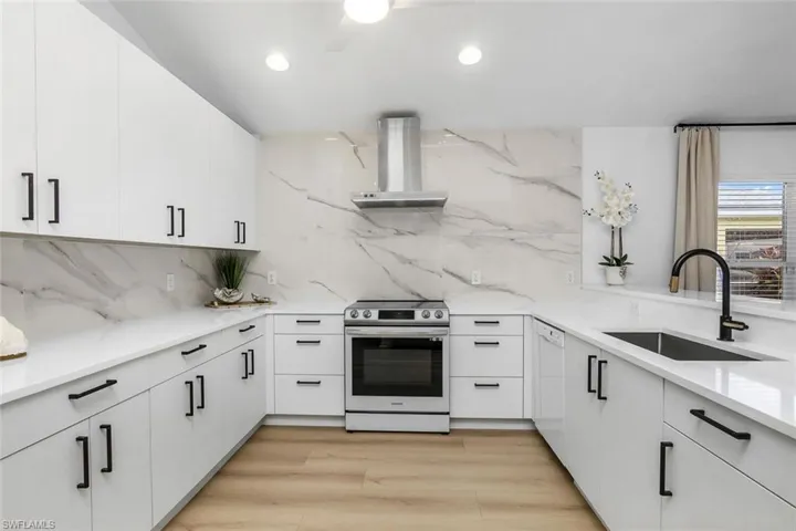Kitchen featuring range hood, stainless steel electric range oven, light hardwood / wood-style flooring, sink, and tasteful backsplash