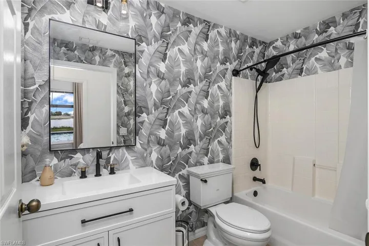 Full bathroom featuring tiled shower / bath, toilet, tile walls, decorative backsplash, and vanity
