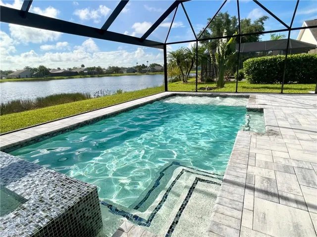 View of swimming pool featuring glass enclosure and a water view