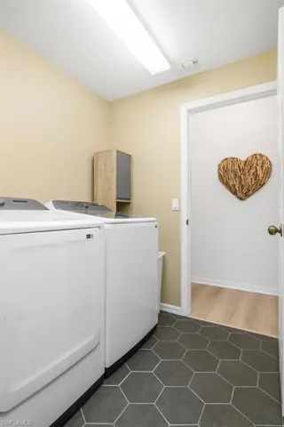 Clothes washing area featuring dark tile patterned flooring and independent washer and dryer