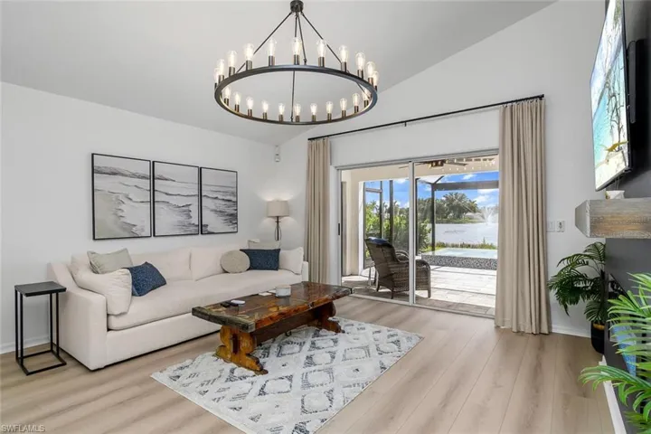 Living room featuring light wood-type flooring, lofted ceiling, and a notable chandelier