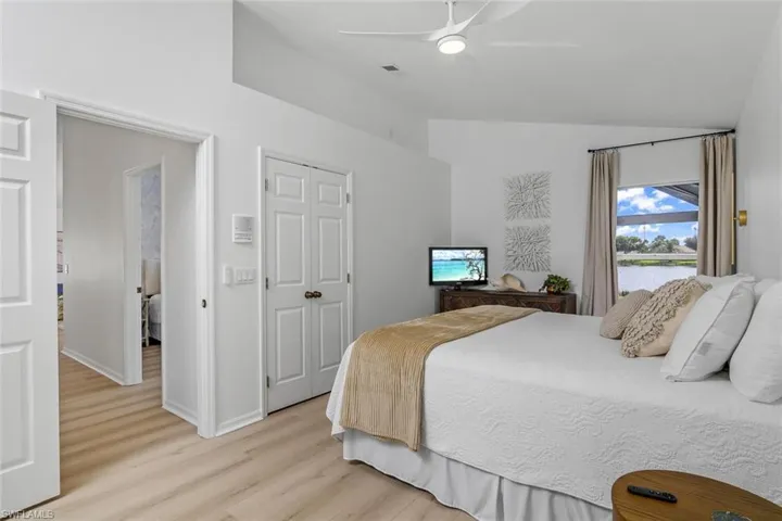 Bedroom with a closet, ceiling fan, light hardwood / wood-style floors, and vaulted ceiling