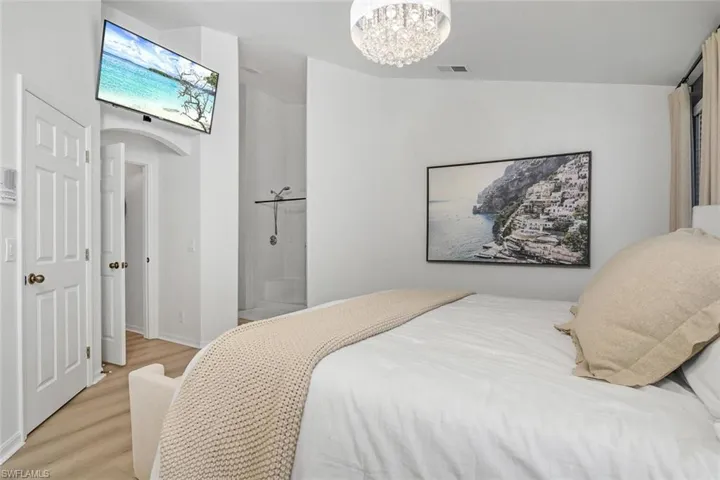 Bedroom featuring vaulted ceiling, a chandelier, and light hardwood / wood-style flooring