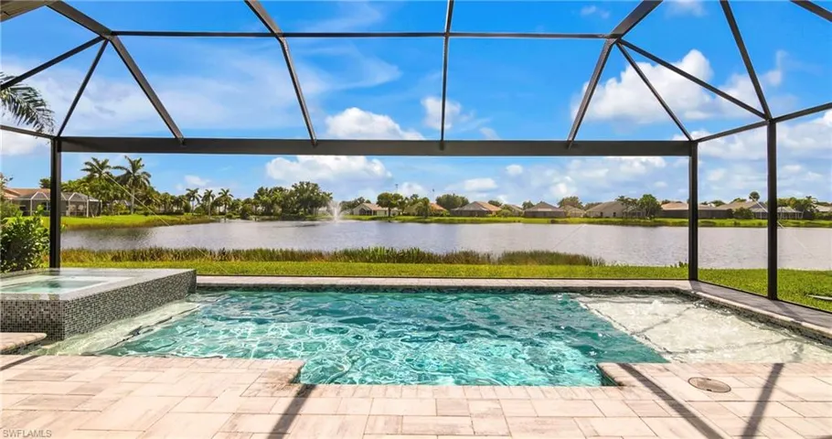 View of swimming pool with a lanai, a water view, and an in ground hot tub