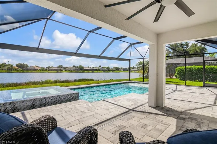 View of swimming pool with a water view, an in ground hot tub, ceiling fan, a patio, and glass enclosure