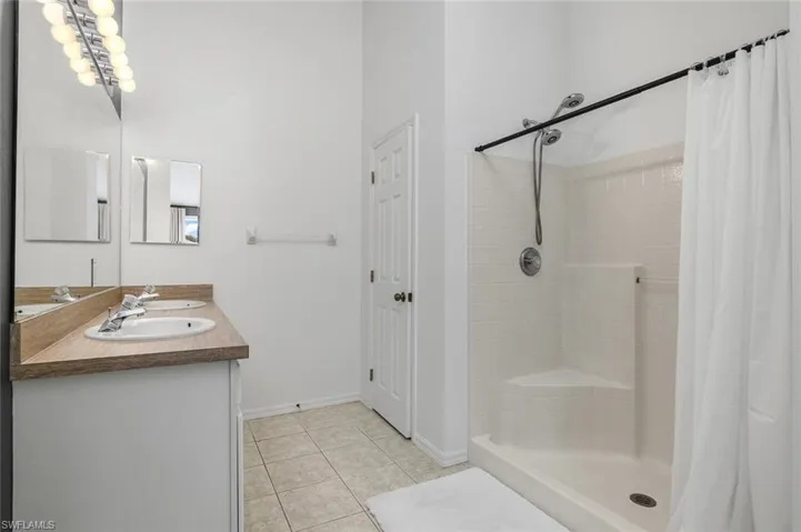 Bathroom featuring tile patterned flooring, vanity, and curtained shower