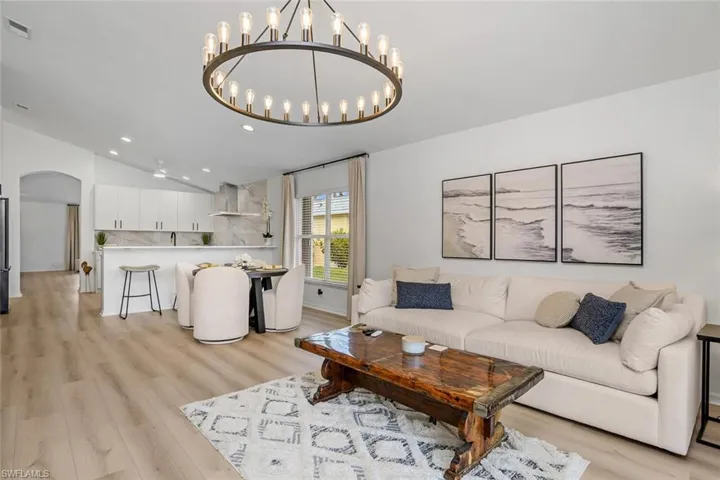 Living room featuring lofted ceiling, light hardwood / wood-style floors, and a notable chandelier