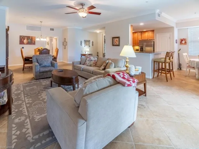 Living room featuring crown molding, light tile patterned floors, and ceiling fan with notable chandelier