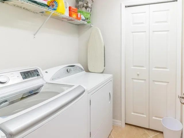 Clothes washing area featuring separate washer and dryer and light tile patterned floors