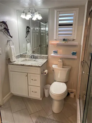 Bathroom featuring vanity, a shower with shower door, and toilet