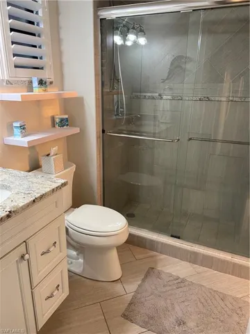 Bathroom featuring an enclosed shower, vanity, and toilet