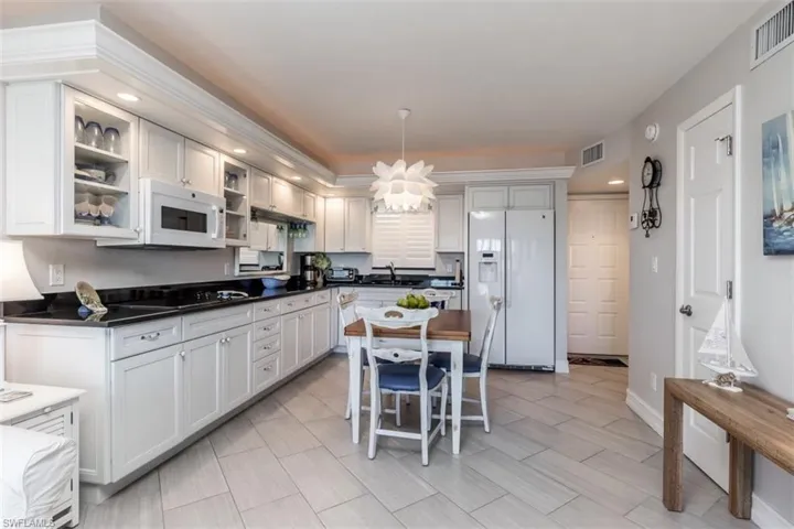Kitchen featuring white cabinetry, sink, a chandelier, pendant lighting, and white appliances