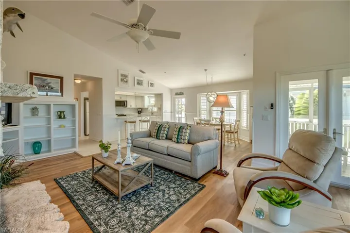 Living room featuring a ceiling fan, light wood finished floors, and vaulted ceiling