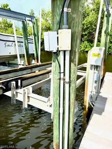 Dock area featuring boat lift, water and electric at dock