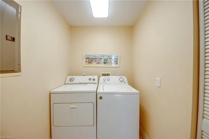 Laundry area featuring electric panel and washer and clothes dryer