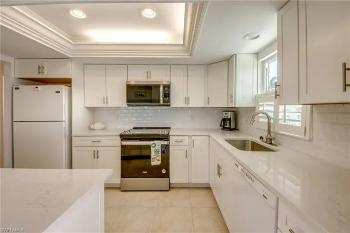 Kitchen featuring stainless steel appliances, light stone counters, white cabinets, tasteful backsplash, and crown molding