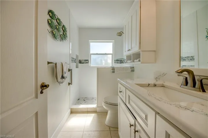 Bathroom featuring vanity, tiled shower, and light tile patterned floors