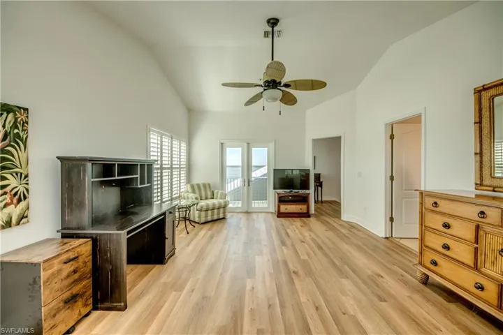 Primary suite with vaulted ceiling, light wood finished floors, and ceiling fan