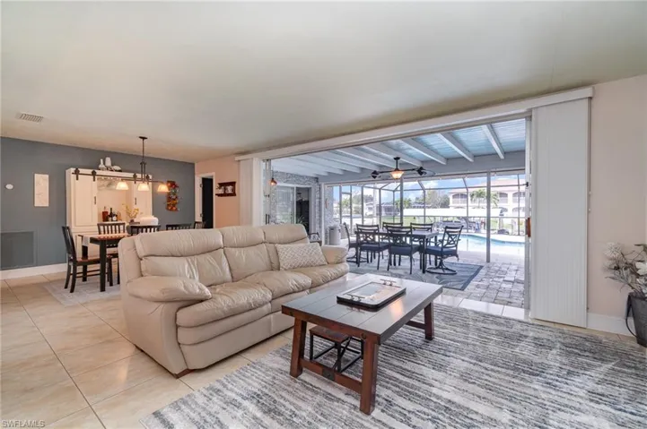 Tiled living room featuring beamed ceiling and an inviting chandelier