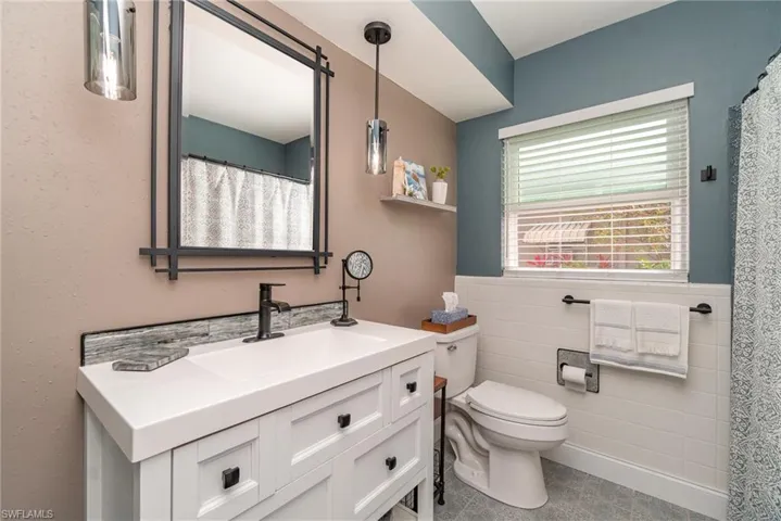 Bathroom with vanity, toilet, and tile walls