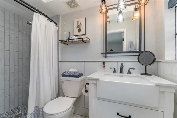 Bathroom with vanity, a shower with curtain, and toilet