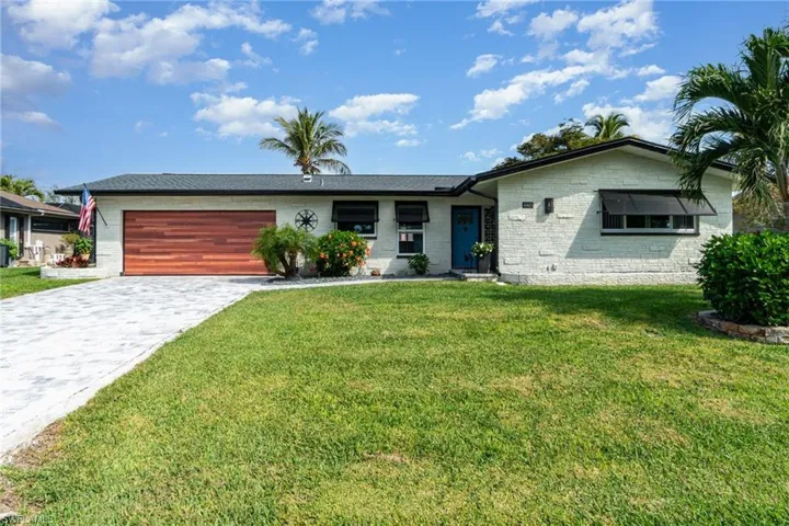 Single story home with a garage and a front lawn