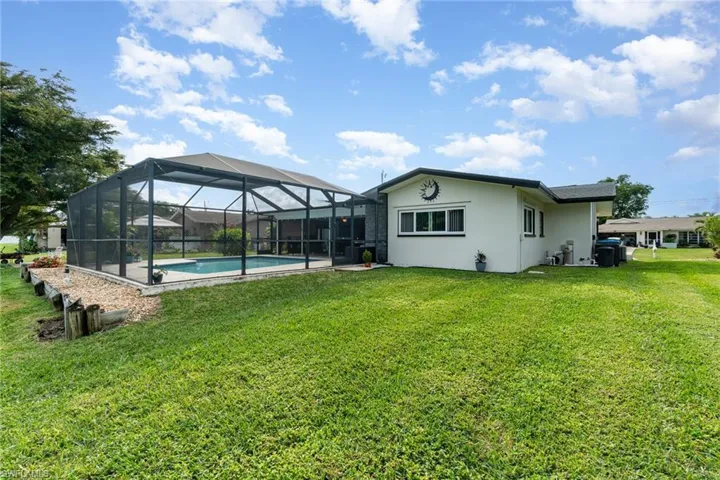 Rear view of house featuring a lanai and a lawn