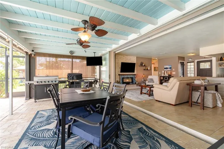 Sunroom with beamed ceiling, a large fireplace, and ceiling fan