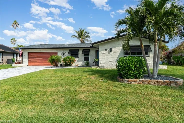 Ranch-style home featuring a garage and a front lawn