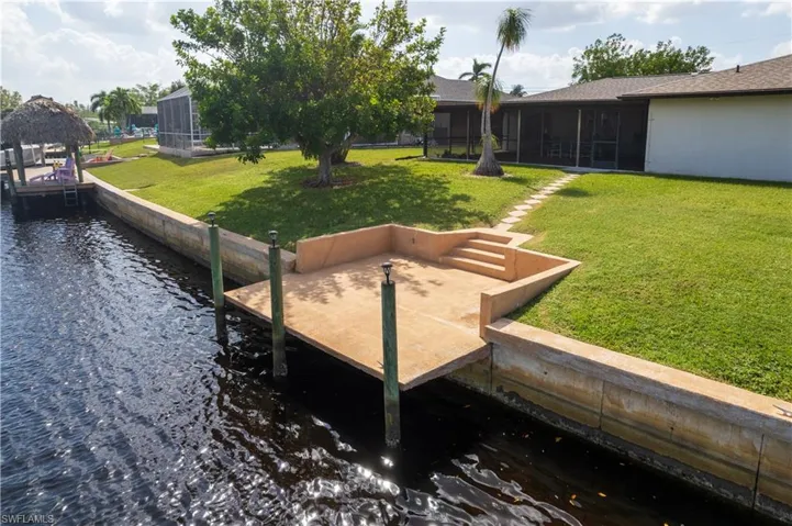 Dock area with a lanai, a yard, and a water view