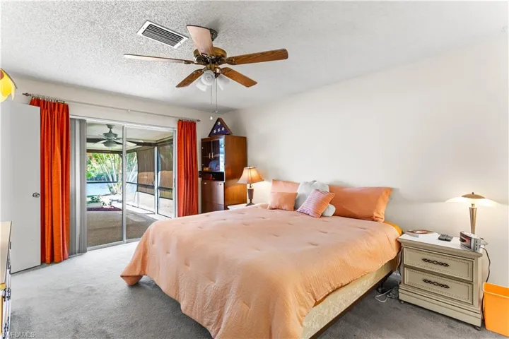 Carpeted bedroom with access to exterior, a textured ceiling, and ceiling fan