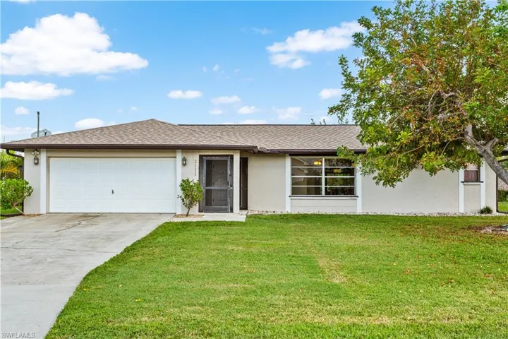 Ranch-style home featuring a garage and a front lawn