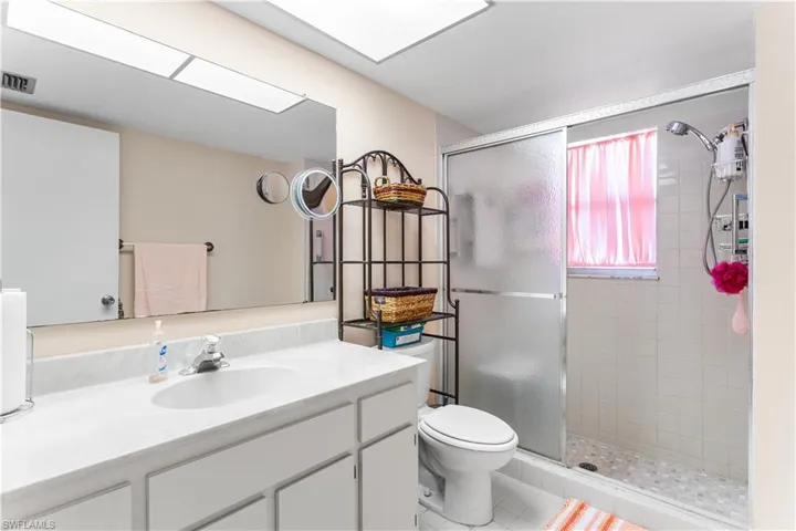 Bathroom with toilet, vanity, tile patterned floors, and a shower with door