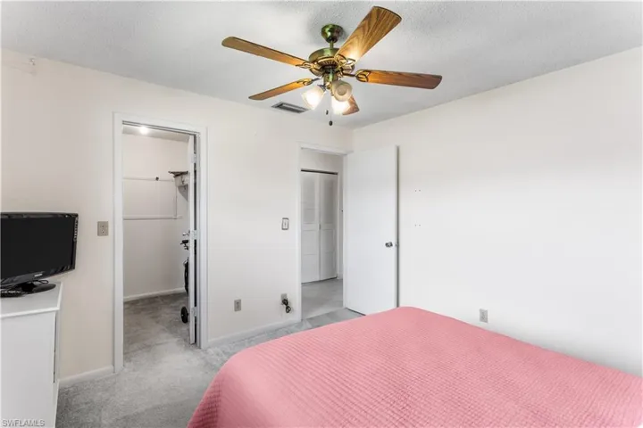 Bedroom featuring a closet, a spacious closet, a textured ceiling, light colored carpet, and ceiling fan