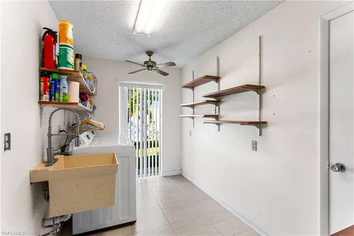 Clothes washing area with ceiling fan, a textured ceiling, and washer and clothes dryer
