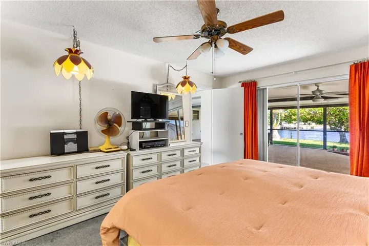 Carpeted bedroom featuring access to outside, a textured ceiling, and ceiling fan
