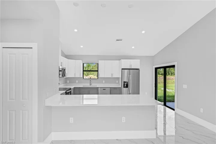 Modern kitchen featuring two-tone cabinetry, stainless steel appliances, and a central island with a solid surface countertop